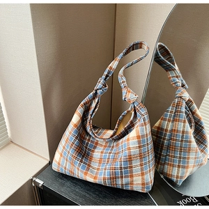 Detail shot of the checkered tote bag's knotted handle and soft wool-like fabric texture