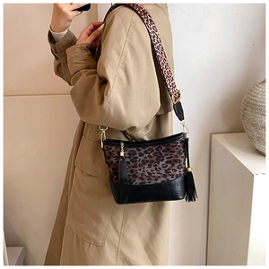 Close-up of leopard print bucket bag with wide shoulder strap and black tassel detail