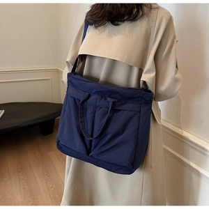 Deep blue large capacity nylon tote bag shown in a lifestyle shoulder carry pose