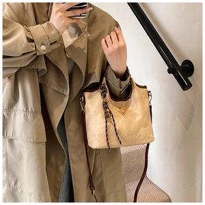 Détail du sac fourre-tout crème avec bordure marron et breloque tressée en situation réelle