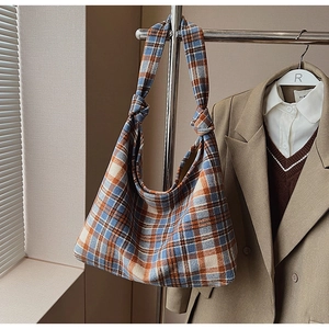 Detail of checkered tote bag featuring a decorative knotted shoulder strap and large capacity