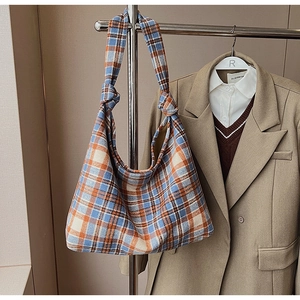 Detailed view of checkered wool tote bag featuring a decorative knotted handle design