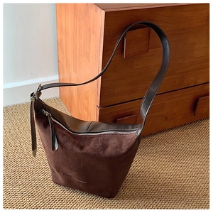 Detailed close-up of a brown suede hobo bag with leather trim and silver zipper