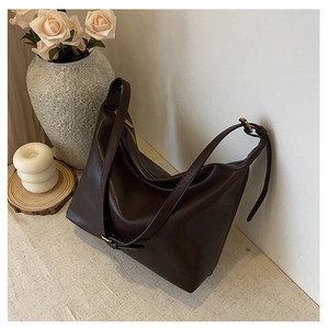 Detail of soft brown leather tote with smooth texture and adjustable shoulder strap