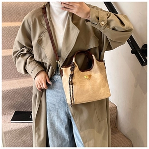 Détail d'un sac cabas trapèze beige avec finitions marron et breloque tissée décorative