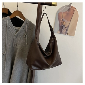 Close-up of a large vintage dark brown leather crescent shoulder bag hanging on a wooden hanger
