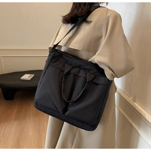 Detail of large black crossbody tote bag showing spacious capacity and wide strap on model