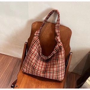Detail of checkered tote bag with knotted handle on a vintage wooden chair