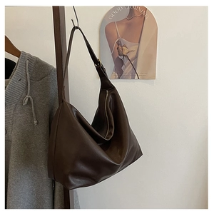 Detail of a large dark brown leather hobo bag with a zipper and wide shoulder strap