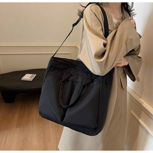 Detail of a large black tote bag with multiple pockets and adjustable shoulder strap
