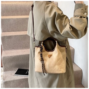 Détail du sac cabas beige avec texture daim, logo triangle et accessoire en corde