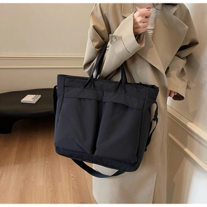 Macro detail of black large capacity tote bag with front pockets and adjustable strap