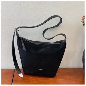 Detailed close-up of a black suede and leather hobo bag with silver metallic hardware
