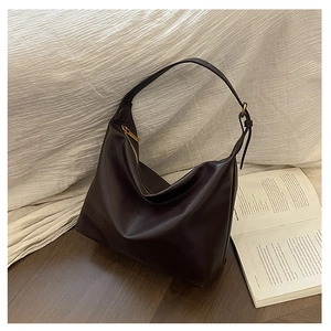 Detailed view of the dark brown leather texture and gold zipper of the large tote bag