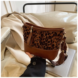 Detail view of leopard print bucket bag with brown leather base and wide strap