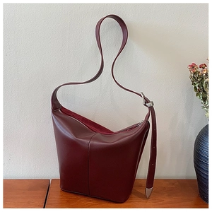 Detailed macro view of burgundy matte leather bucket bag with silver metal buckle details