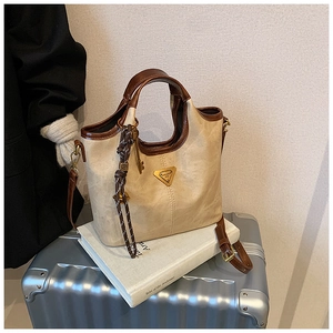 Détail du sac cabas beige rétro sur valise avec bordure cuir et logo triangulaire