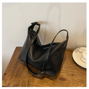 Close-up of a large black vintage leather shoulder bag with metallic zipper and adjustable strap