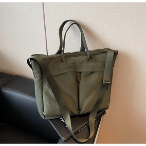 Detail view of large army green nylon tote bag with two spacious front utility pockets