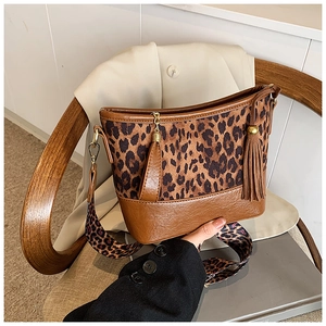 Detail of leopard print stitching, brown leather base, and stylish tassels on bucket bag