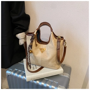 Détail du sac cabas vintage avec logo en métal et breloque sur fond de livre blanc