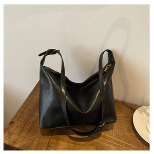 Detail view of the black leather hobo bag with a gold buckle and adjustable strap