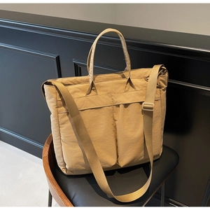 Detail of khaki nylon tote bag with functional pockets on a chair in a minimalist setting