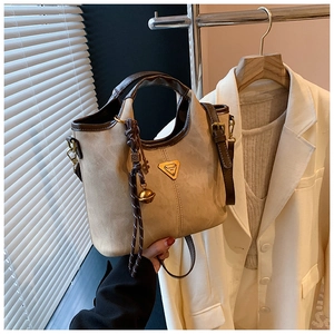 Détail du sac cabas beige en similicuir avec bordure marron, logo doré et clochette