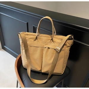 Close-up of khaki tote bag featuring large front pockets and adjustable strap detail