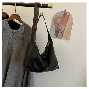 Close-up of black leather hobo bag with gold zipper hanging on a wooden hanger