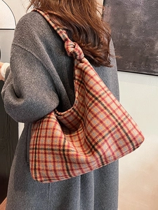 Plaid woolen tote bag with a knotted strap shown on model's shoulder in a lifestyle setting
