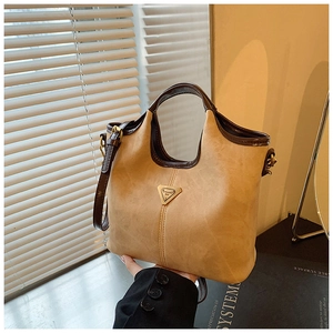 Détail du sac cabas en daim beige avec bordures contrastées et logo triangulaire doré