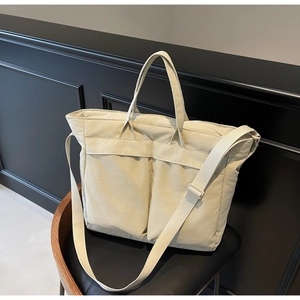 Detail of beige large capacity nylon tote bag with dual front pockets and wide strap