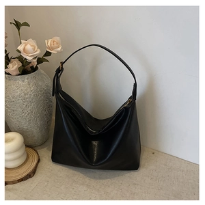 Close-up of black retro dumpling bag with fine leather texture and wide shoulder strap