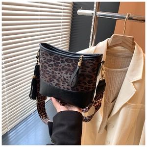 Detailed close-up of leopard print bucket bag with black fringe and wide shoulder strap