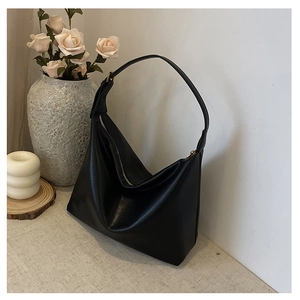 Detail of minimalist black PU leather hobo bag with gold zipper in a lifestyle setting