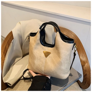 Détail d'un sac cabas rétro kaki avec logo triangle doré et liserés noirs contrastés