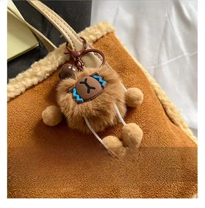 Détail d'un porte-clés ours en peluche marron attaché à un sac à main en daim