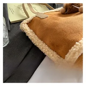 Détail du sac cabas en daim marron avec bordure en fausse fourrure et pompon doux