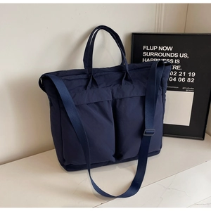 Detail of dark blue nylon tote bag showing durable texture and functional front pockets
