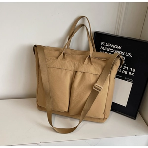Close-up of khaki nylon tote bag showing dual pockets and adjustable wide shoulder strap
