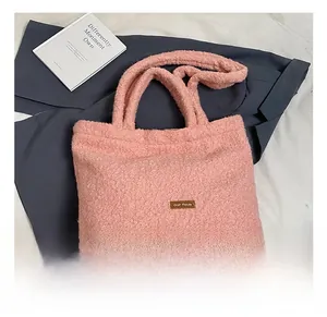 Detail of pink plush tote bag showing the brown leather label and soft lamb wool texture