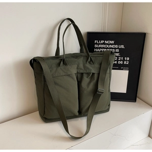Detail of olive green nylon tote bag featuring spacious front pockets and woven strap