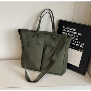 Close-up of army green nylon tote bag featuring front pockets and adjustable strap