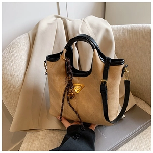 Détails du sac cabas en daim kaki avec finitions en cuir noir et logo Lunaora sur chaise
