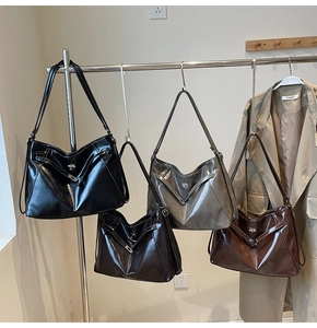 Détail de quatre sacs cabas en cuir brillant de couleurs variées dans un showroom chic