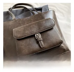Detail of dark brown tote bag with contrast stitching and metal buckle on front pocket