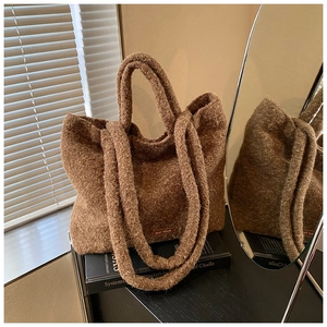 Close-up of brown plush tote bag featuring an embroidered label and fuzzy strap texture