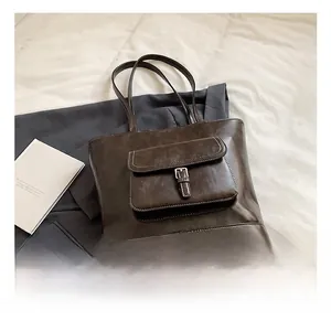 Detailed close-up of dark brown vintage faux leather tote bag with white stitching and pocket
