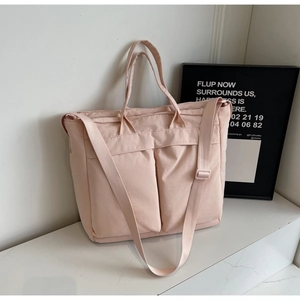 Detailed view of pale pink nylon tote with large cargo pockets and adjustable straps
